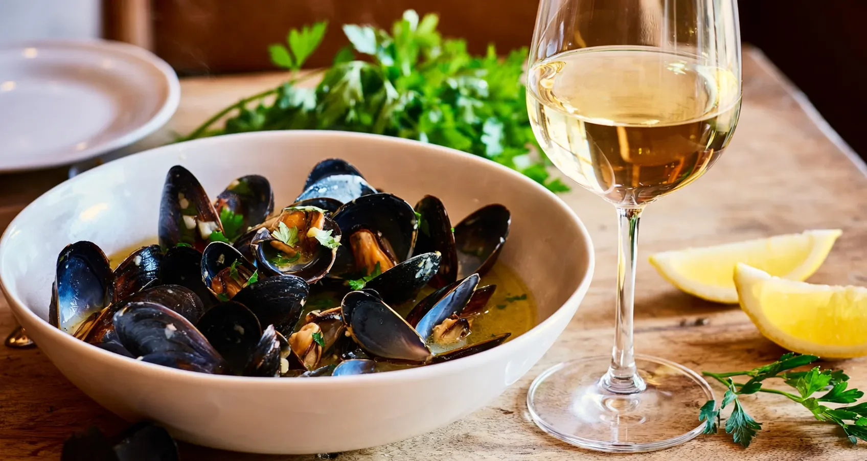 Moules marinières : un classique intemporel de la cuisine française Moules marinières servies dans un bol en céramique avec persil et citron