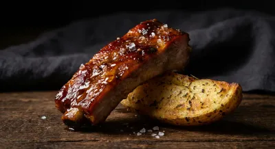 Gros plan sur un travers de porc croustillant et une pomme de terre rôtie