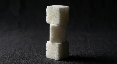 Gros plan minimaliste de morceaux de sucre sur fond noir contrasté.