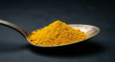 Cuillère d'épice jaune vif sur fond noir