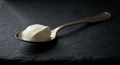 Gros plan d'une cuillère de fromage blanc sur fond sombre contrasté