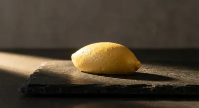 Gros plan minimaliste sur une quenelle dorée sur fond sombre.