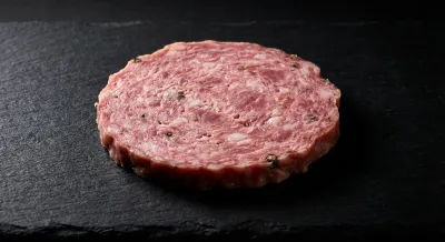 Gros plan iconique d'une tranche de saucisson à cuire sur fond noir